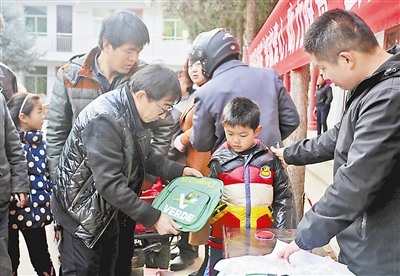 图为爱心人士为孩子们送上新书包