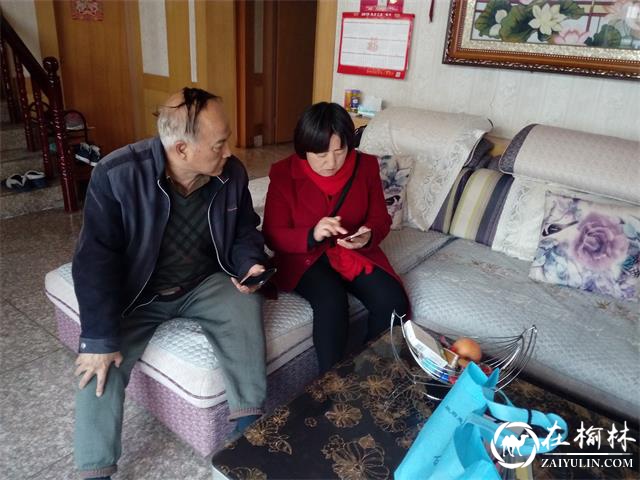 社区工作人员给老党员演示怎么使用学习强国