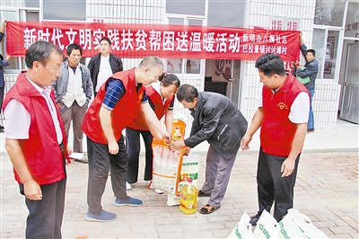 图为志愿者给贫困户发放慰问品。