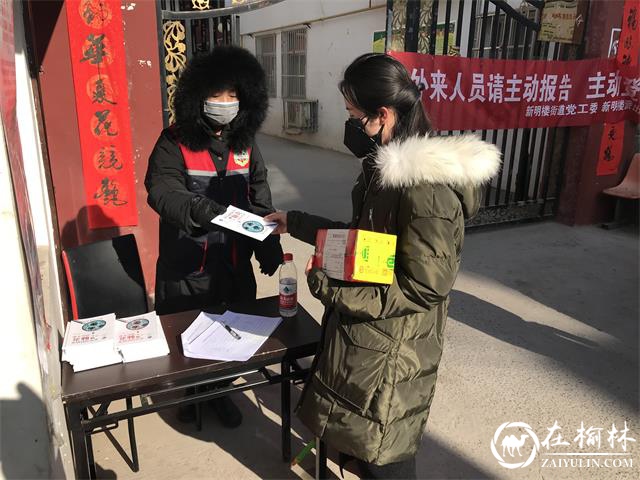 社区网格员为小区进出居民发放疫情防护宣传手册,并精细为出入人员消毒