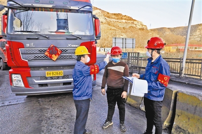 图为志愿者正在对进出矿区运煤的人员进行体温测量。