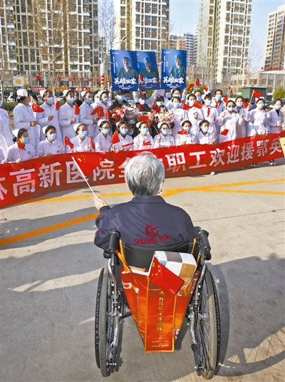 在欢迎我市首批援鄂医护人员回家的现场,这位坐着轮椅的老人,手持国旗,喜迎英雄回家。