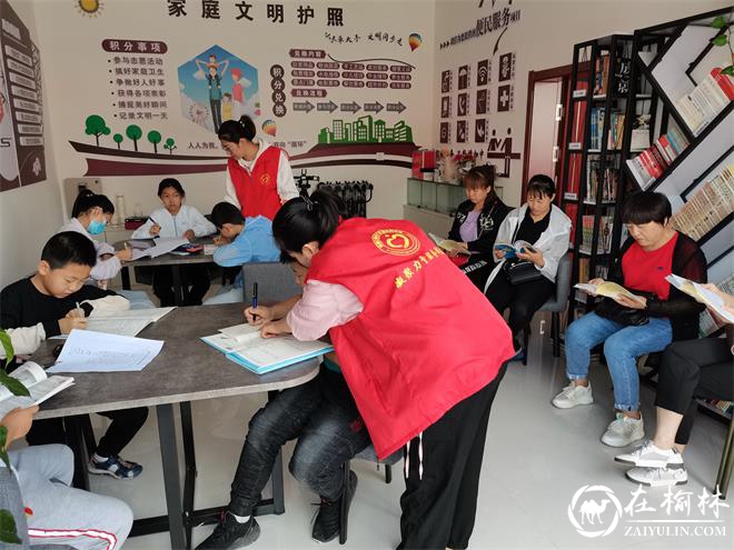 志愿者辅导孩子们暑假作业，家长们在阅读