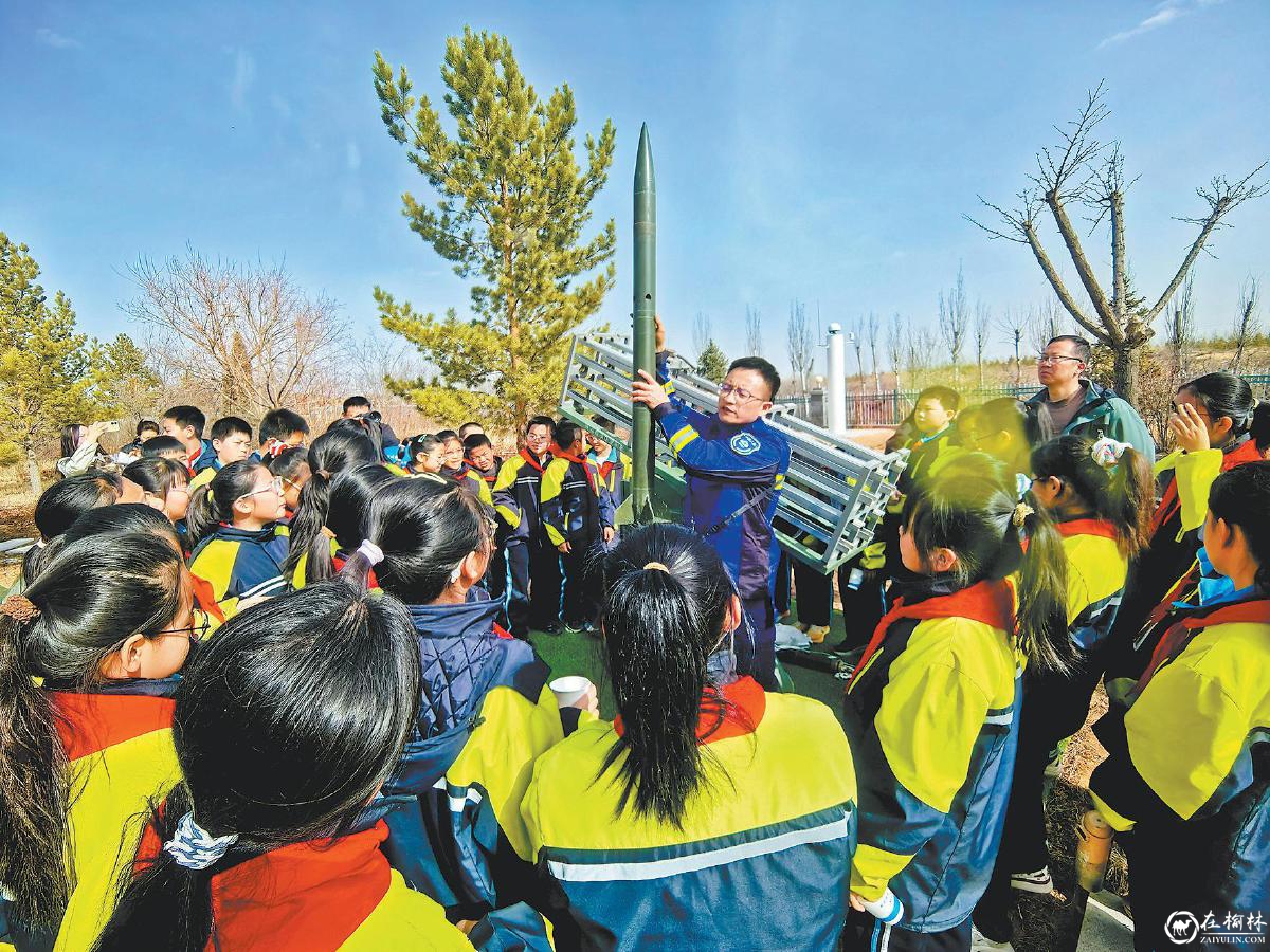 图为市人工增雨（雪）基地工作人员向孩子们讲解人工增雨火箭相关知识。　慕荣摄