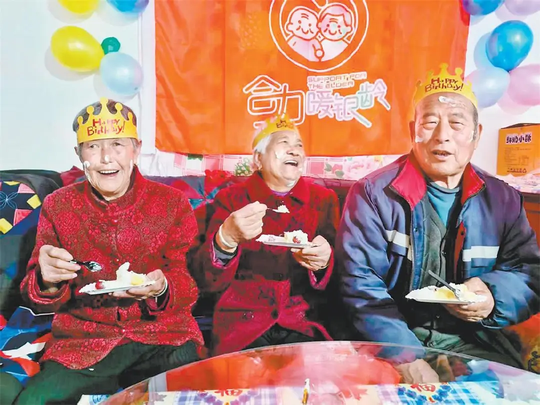 三位老人在品尝生日蛋糕。李欢欢摄