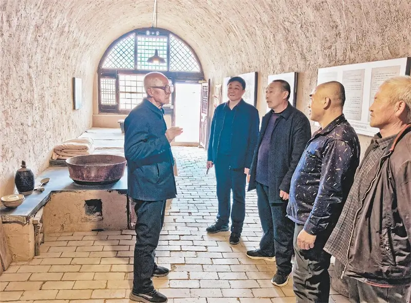在沟口村红军东征指挥所旧址，李玉林（左一）给参观者讲述红色故事。张丹摄