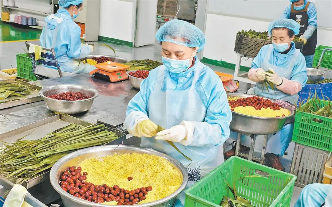 绥德县惠小萌食品有限公司的员工在包制牛角粽。王姣摄