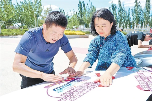 李扬(左)和张莹夫妻俩给车辆张贴爱心送考标识。卢云云摄