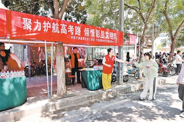 图为志愿者为考生发放饮用水。郑懿摄