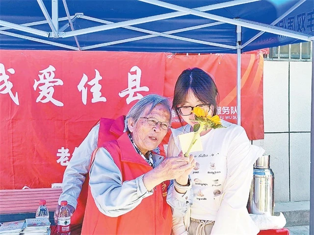 图为路生梅(左)为考生赠送鲜花。 邸金波摄