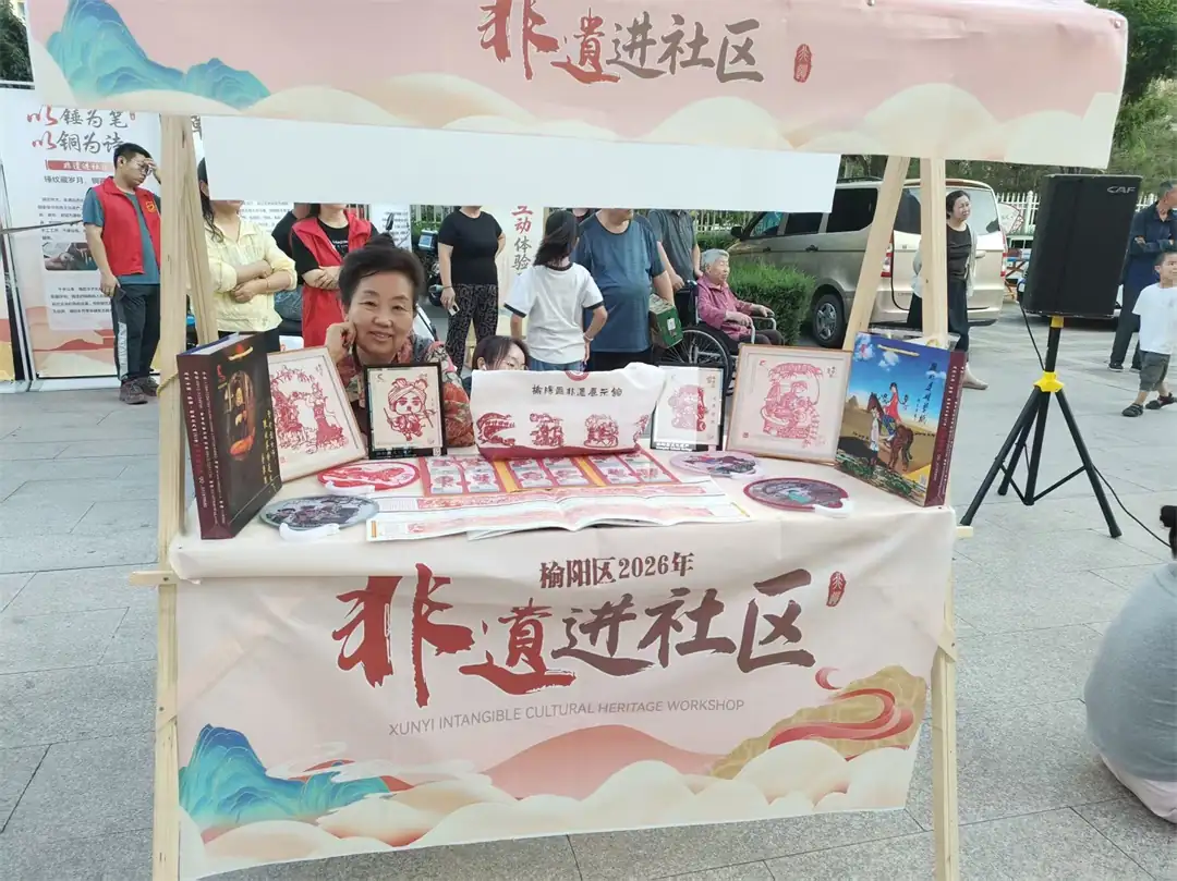 8月9日，榆阳区金沙路街道金榆社区开展“非遗进社区”惠民活动，以二人台、民俗小品等文艺汇演搭配非遗市集，并开设剪纸体验课堂，居民老少同乐巧手创作。